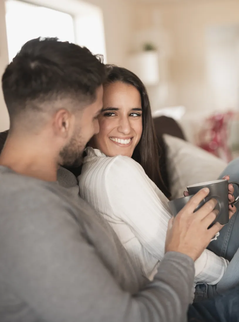 Família sorrindo reunida no sofá de casa
